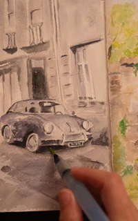 a person is drawing a car in a watercolor sketchbook